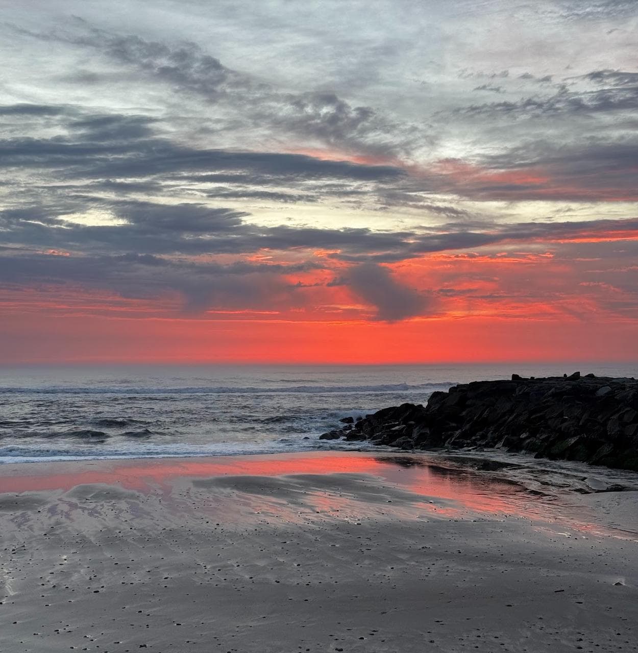 Pôr do sol na praia da Apúlia com reflexo no areal.